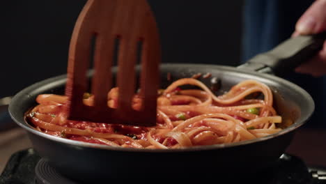 cooking pasta with wooden spoon