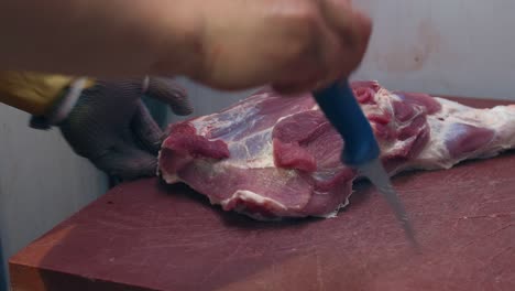 el carnicero corta la carne de la pierna de cerdo con un cuchillo