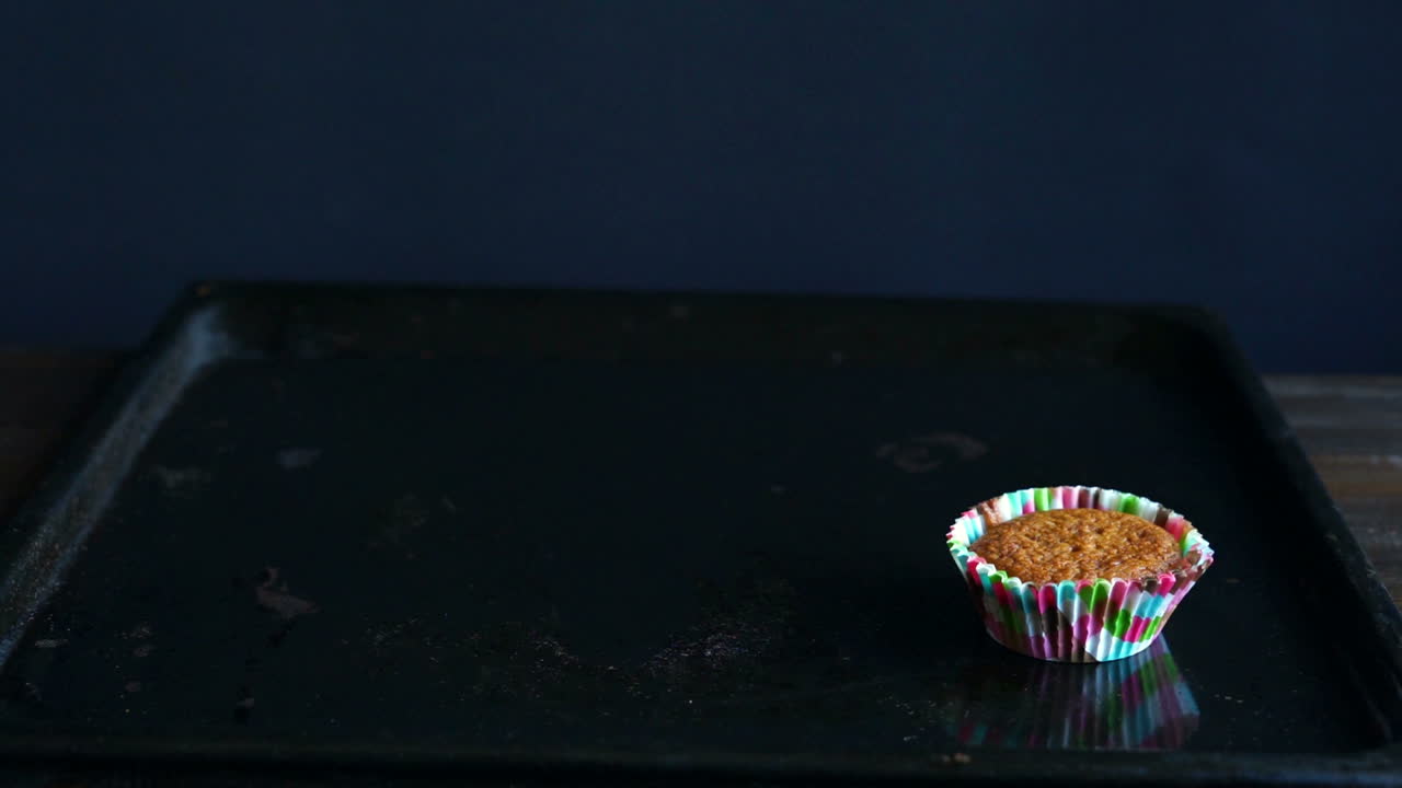 Chef che toglie l'ultimo cupcake dalla teglia. Un cupcake sulla teglia