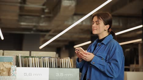 a young attractive woman in a blue shirt stands in a construction supermarket and chooses a product a young attractive woman in a blue shirt stands in a construction supermarket and chooses a product thoughtful woman on the background of household goods and repairs