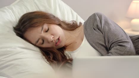 침실에서 노트북 컴퓨터에서 일하는 피곤한 여자. 슬픈 여자 침대에서 깨어