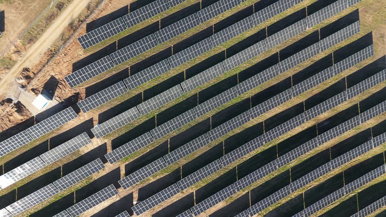 Aerial footage of solar panels plant a generating green electric energy on a wide green field on a sunny day, in Taurage, Lithuania, top down shot