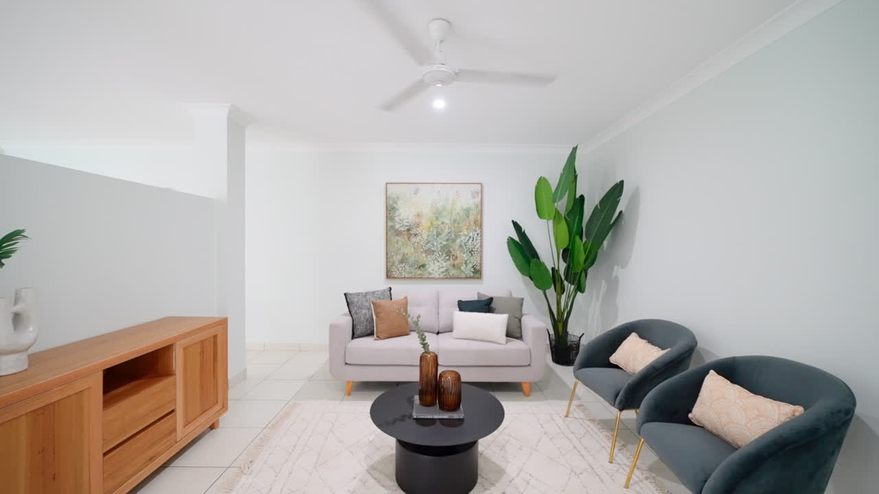 Piccolo salotto con arte murale di piante tropicali e mobile TV in legno vuoto