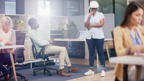 using vr headset, woman standing in office while colleagues work around her