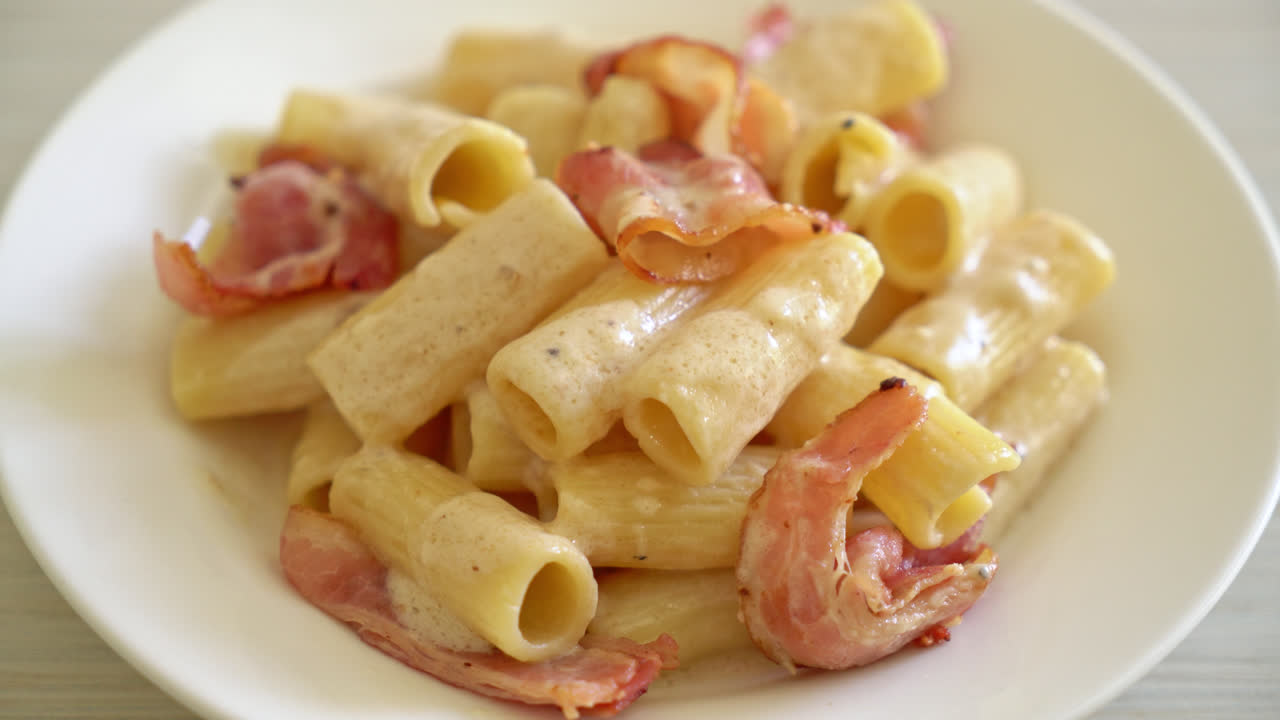 espaguetis rigatoni caseros con salsa blanca y tocino - estilo de comida italiana