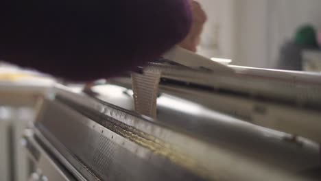 female hands making textile on weaving machine at table in workshop