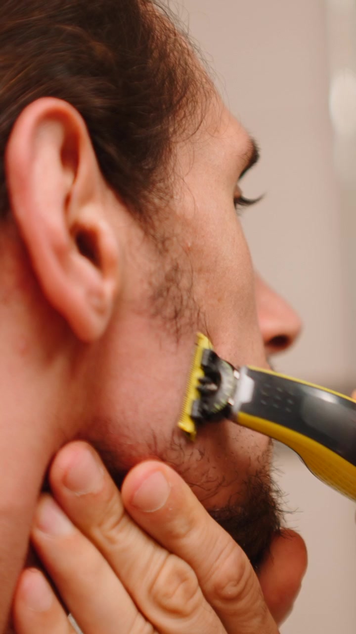 Homem aparando a barba com um barbeador elétrico