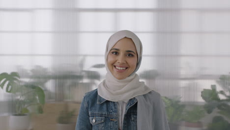 portrait of young muslim business woman looking at camera smiling confident wearing traditional hajib headscarf in office workspace background