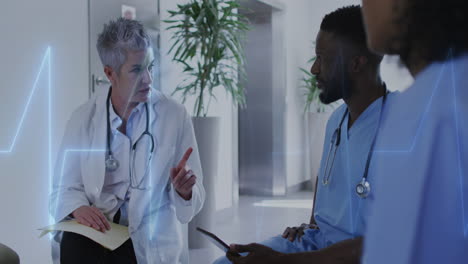 Animation-of-heart-rate-monitor-on-caucasian-female-doctor-discussing-with-healthworkers-at-hospital