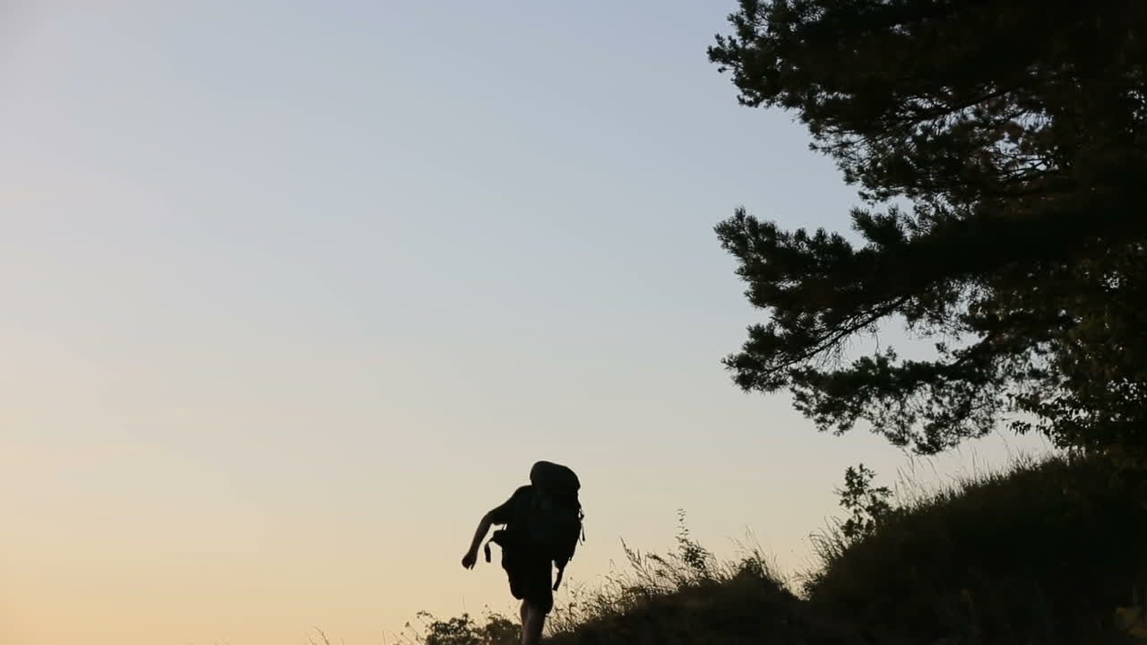 Escursionista che sale sulla collina. Vista posteriore di un escursionista che sale sulla collina di sera.