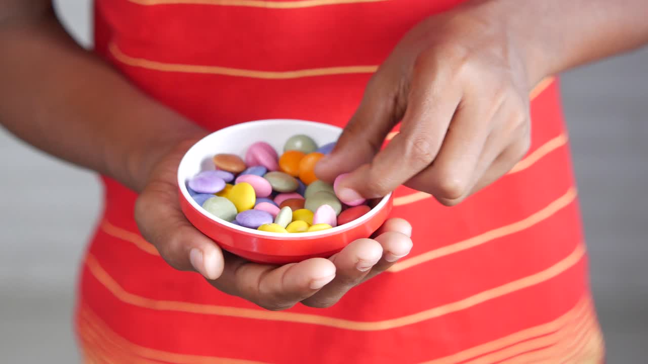 Bambino che mangia caramelle colorate da una ciotola
