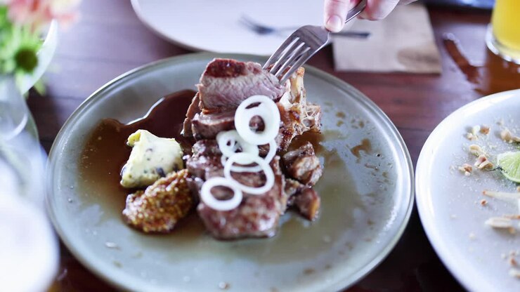 Person slicing and eating steak with garnish