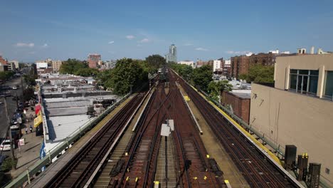 an aerial view of elevated tracks with two trains moving towards the camera on a sunny day