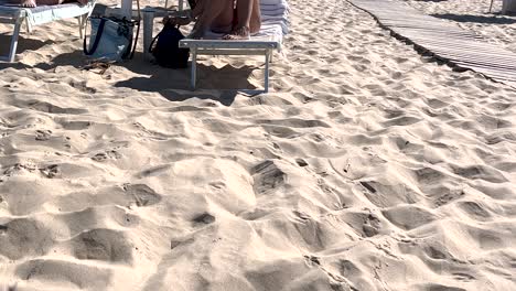 hastily searching for her phone, a woman intends to make a video call to showcase the wonderful beach day she's experiencing, capturing the eagerness to share the moment with others