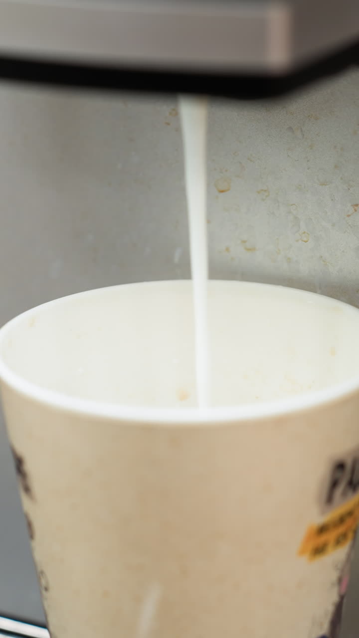 la leche se vierte en una taza de café desde una máquina. centrándose en la corriente de leche que llena la taza, capturando el momento preciso del proceso de preparación del café