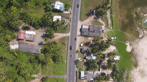 drone shot following a car and motorbike along road on sunny day in sri lanka