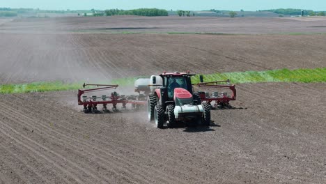 drone footage of a farmer planting corn seeds in an iowa field in a red tractor