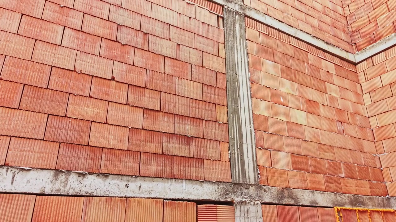 Textured clay brick with beams. Unfinished interior emphasized by rough natural materials. Rustic brick corner featuring concrete elements and textured clay surfaces