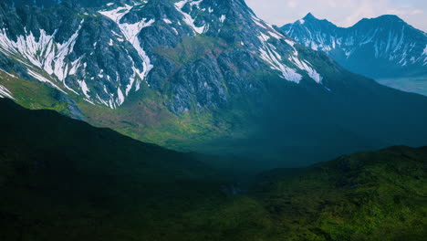 Aerial-Over-Valley-With-Snow-Capped-Mountains-In-Distance