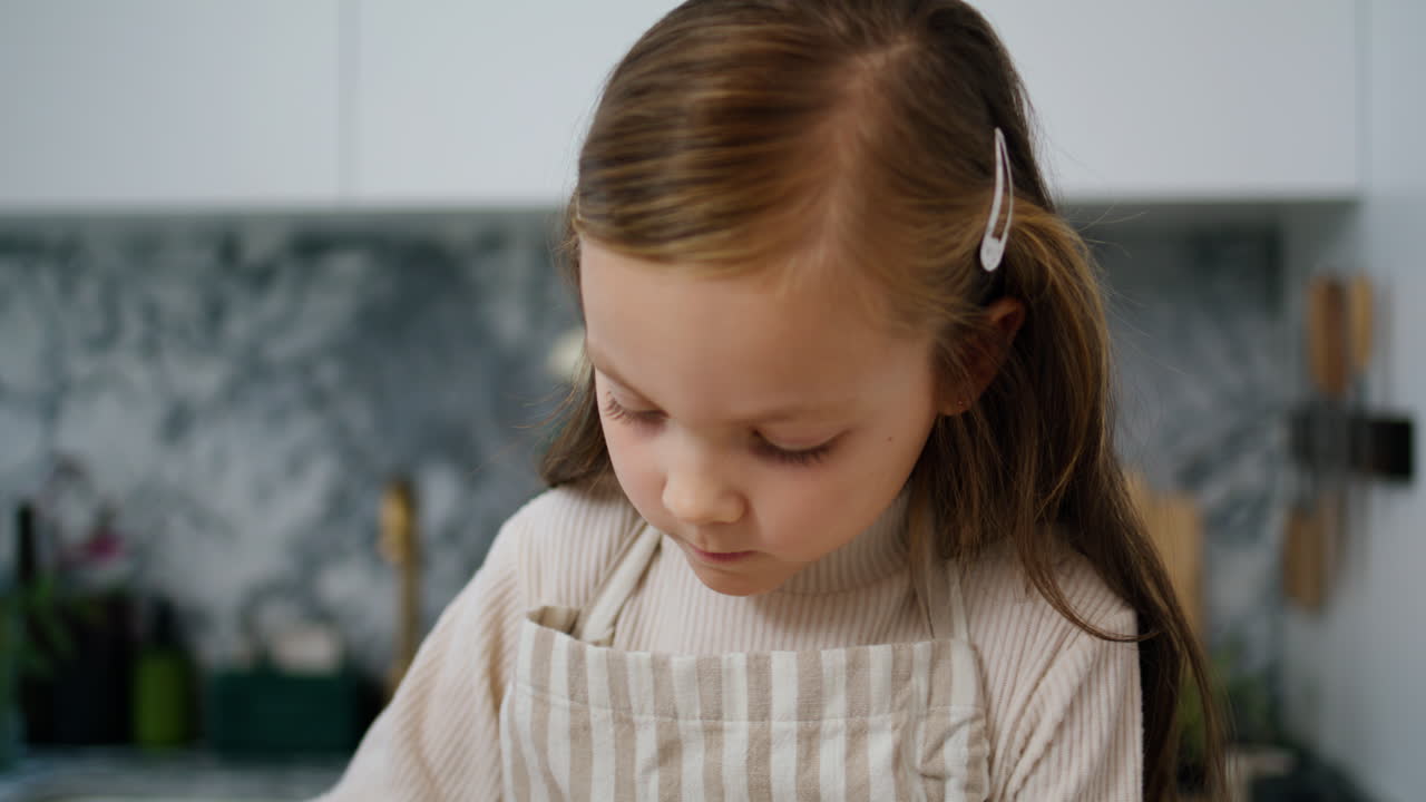 niño enfocado sosteniendo un batidor de cocina en primer plano. niña preparando masa sola