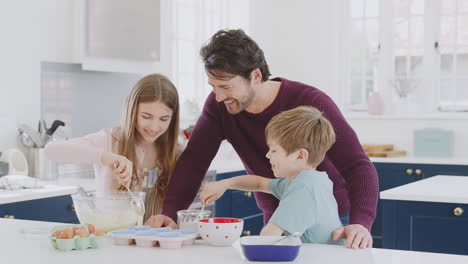 Padre-Con-Dos-Hijos-En-La-Cocina-De-Casa-Divirtiéndose-Horneando-Pasteles-Juntos