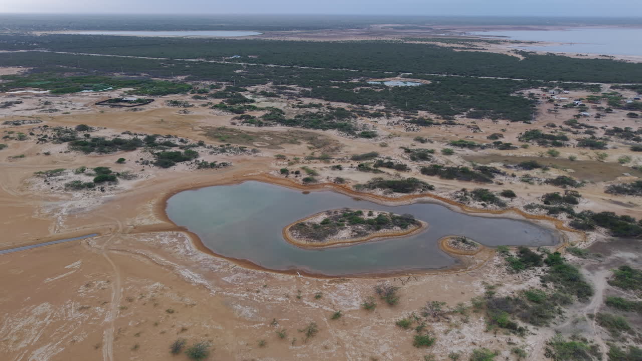 Riprese aeree dello splendido deserto de La Guajira, che mostrano dune di sabbia aspre e specchi d'acqua isolati sotto un cielo vasto. Cattura la serena bellezza del paesaggio unico della Colombia.