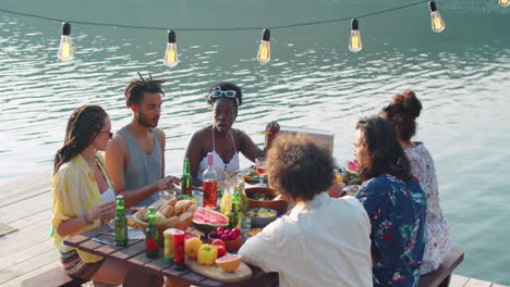 friends having outdoor dinner party on lake pier