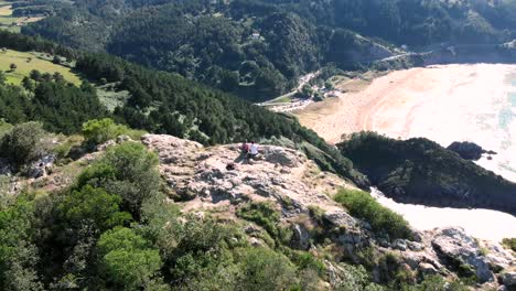 drone parallax shot of a cliff where two hikers are enjoying the nature near cantabrian sea