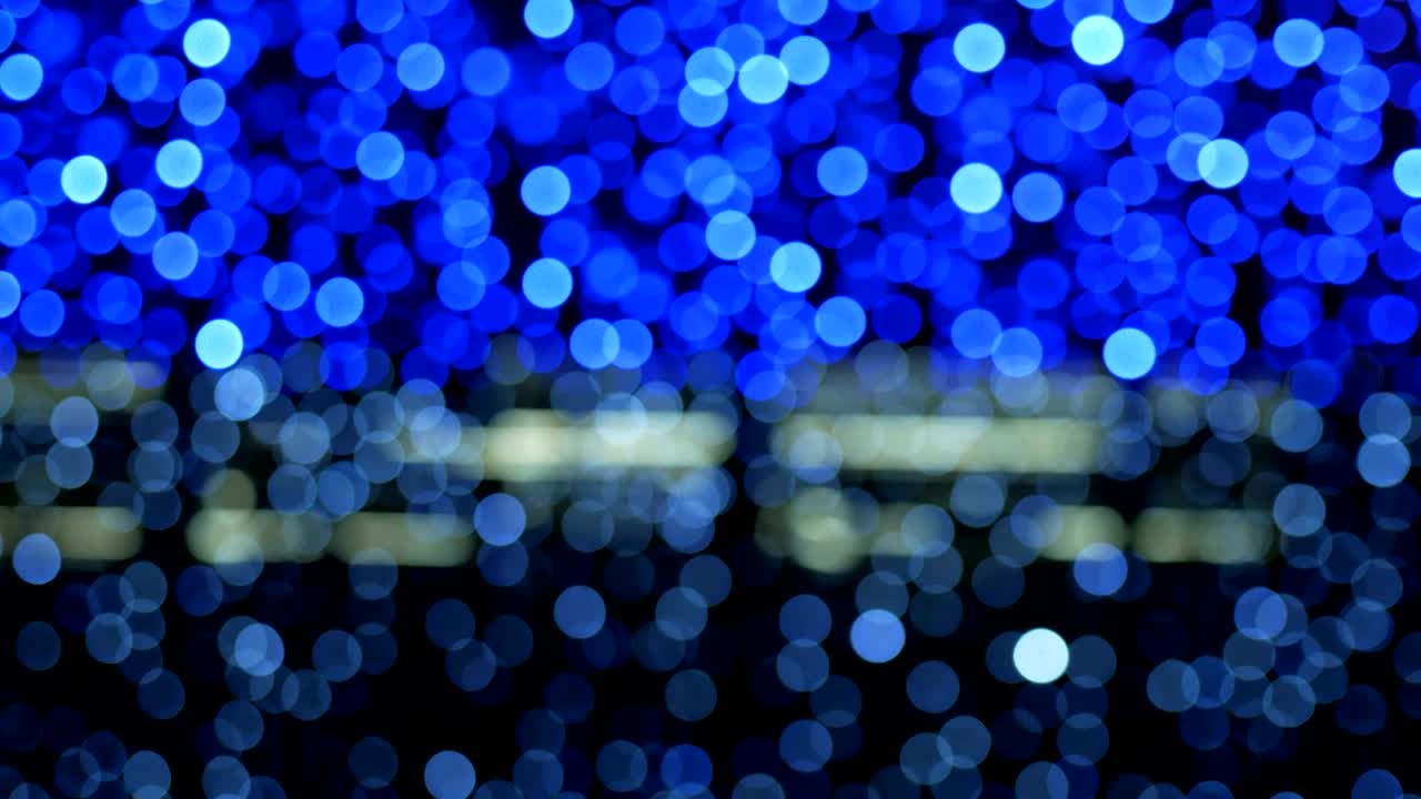 밤의 추상적인 배경은 멋진 보케로 분해되어 있습니다. 흐릿한 크리스마스 조명 보케. 흐릿함을 가로질러 팬.