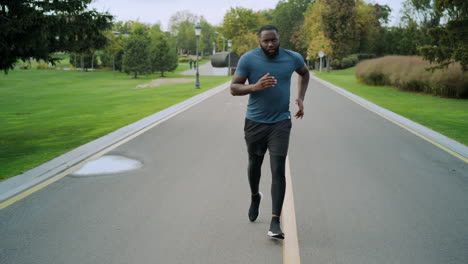 yog man running on road. afro sportsman training in park alone