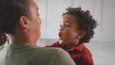 Loving-Mother-Carrying-And-Hugging-Son-At-Home-In-Family-Kitchen