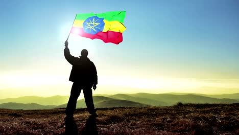 hombre de silueta exitoso ganador agitando la bandera etíope en la cima del pico de la montaña. fondo de bucle de cinemagraph