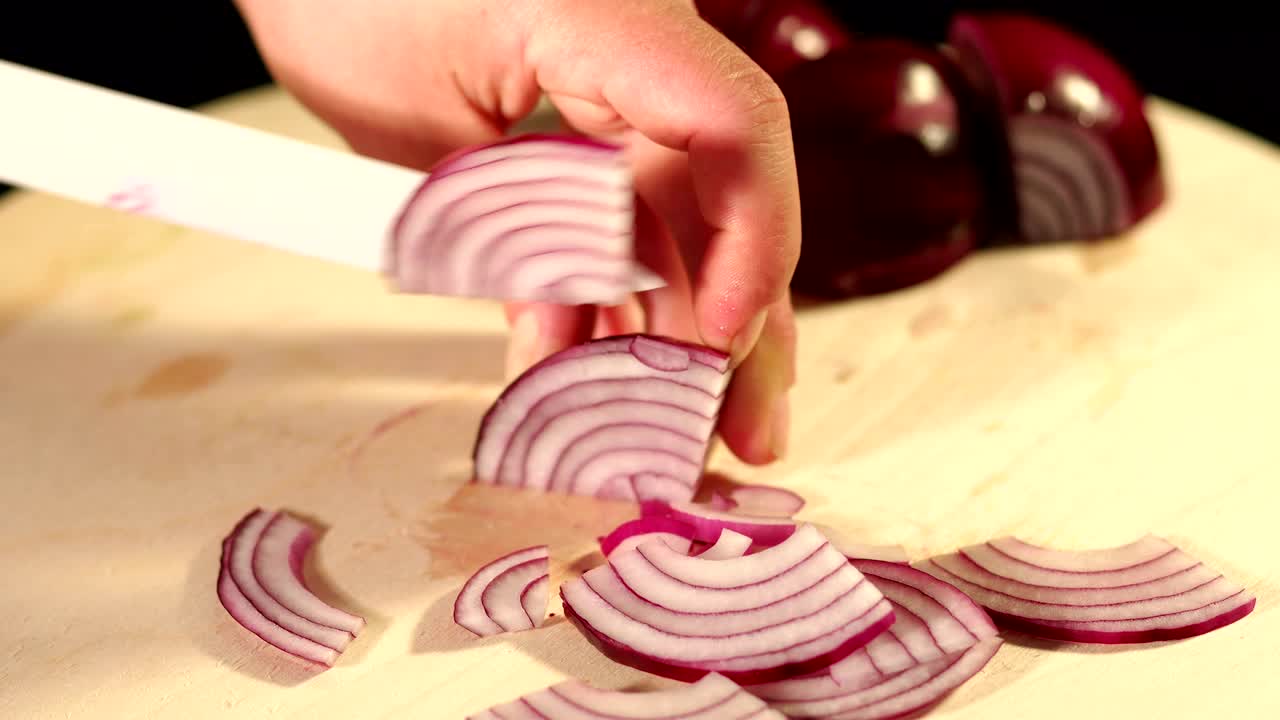 Close-up of a chef cutting red onion on a Board.