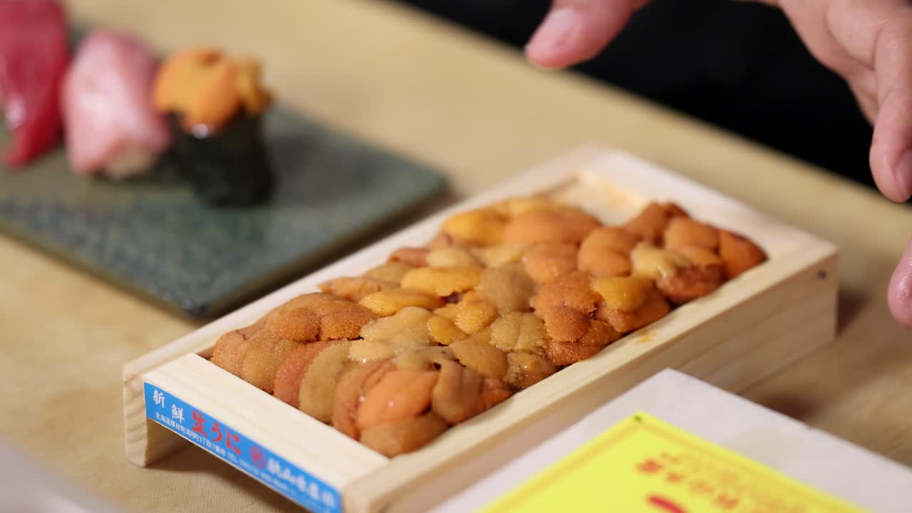新鮮なウニの木箱にふたをするシェフのクローズアップショット