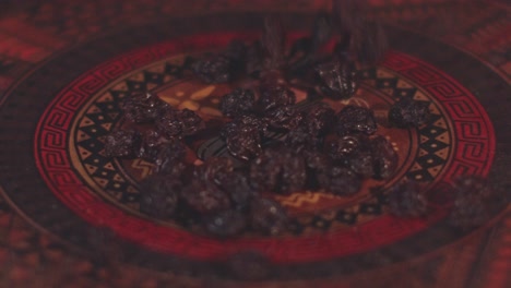 dried raisins fall into a beautifully decorated serving dish