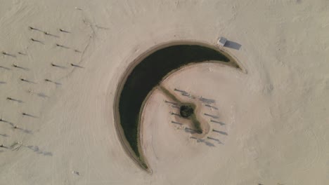 Vista-Aérea-Del-Lago-Lunar-En-Dubai,-El-Lago-En-Forma-De-Luna-Está-En-Medio-Del-Desierto-De-Al-Qudra,-Rodeado-De-Dunas-De-Arena-Dorada-En-Los-Emiratos-árabes-Unidos