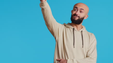 hombre árabe saludando a una persona mientras posa en el estudio