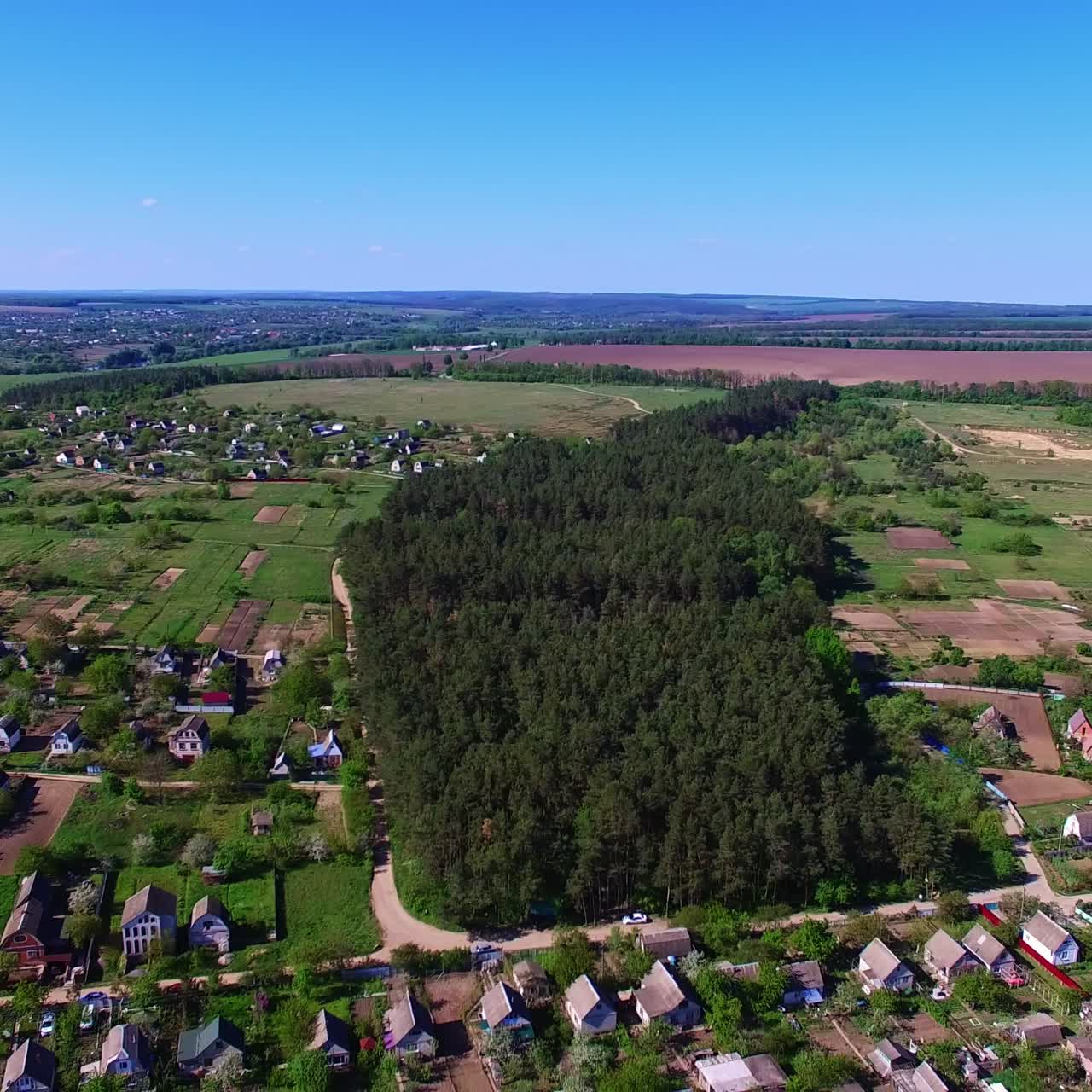 Little forest planting of pine trees in the countryside. Beautiful village with lots of cottages on the bank of the river. Aerial perspective
