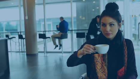 Animation-of-thumbs-up-icons-over-caucasian-woman-drinking-coffee-and-using-laptop-at-cafeteria