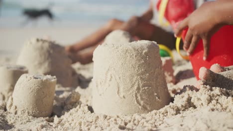 Sección-Media-De-Una-Niña-Afroamericana-Jugando-Con-Arena-En-La-Playa