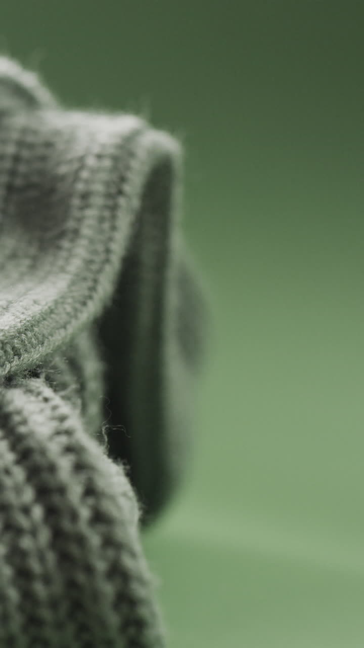 Micro vertical video of green knitted fabric with copy space on green background