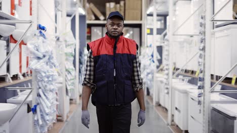 salesman walking between rows in hardware store, looking to the camera