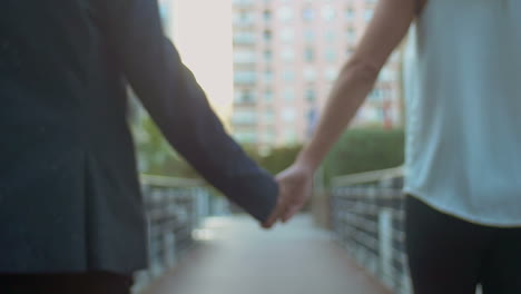 Couple-holding-hands-and-walking-on-street