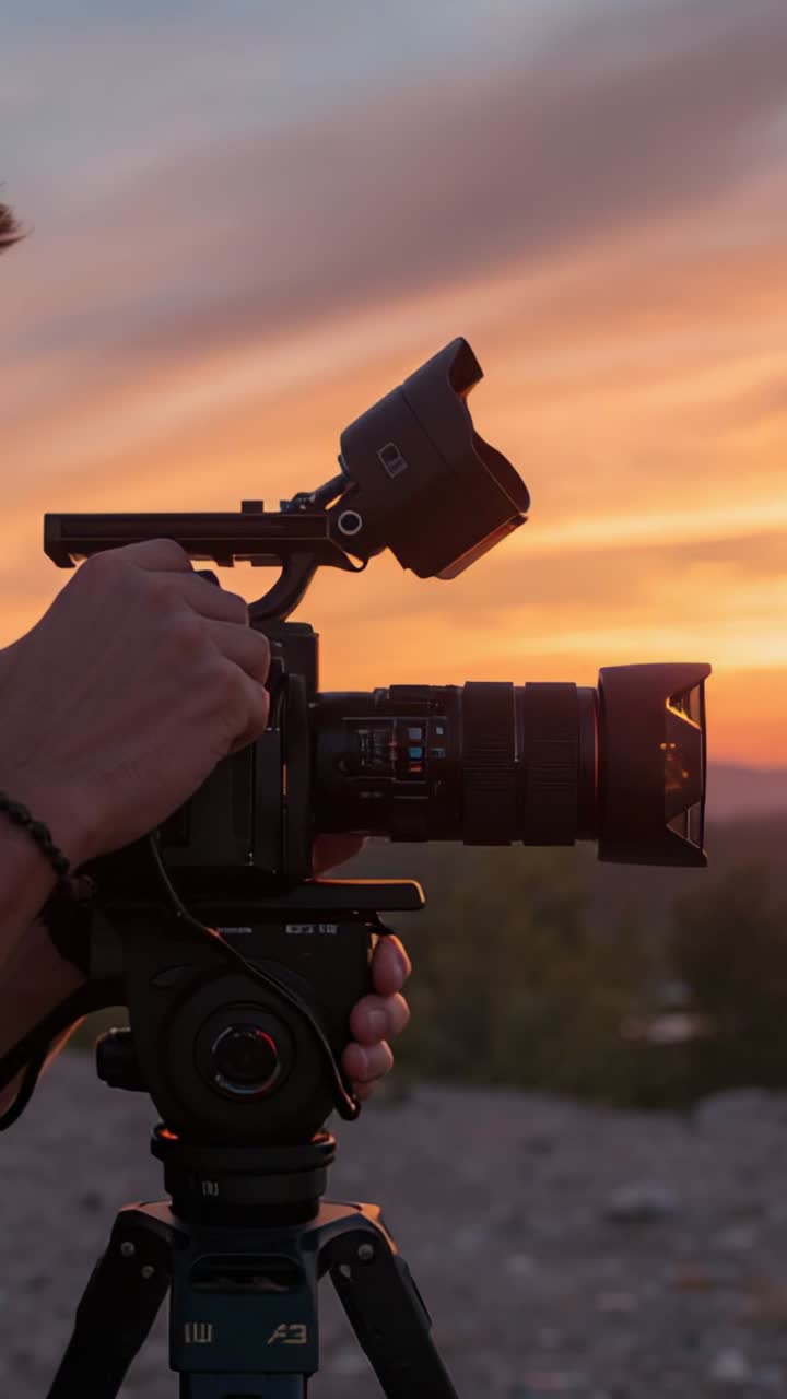 Vertical video: Reacting to sunset, operator flipping viewfinder hood, adjusting focus on gravel