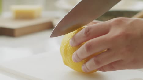 Crop-woman-cutting-fresh-lemon-on-chopping-board