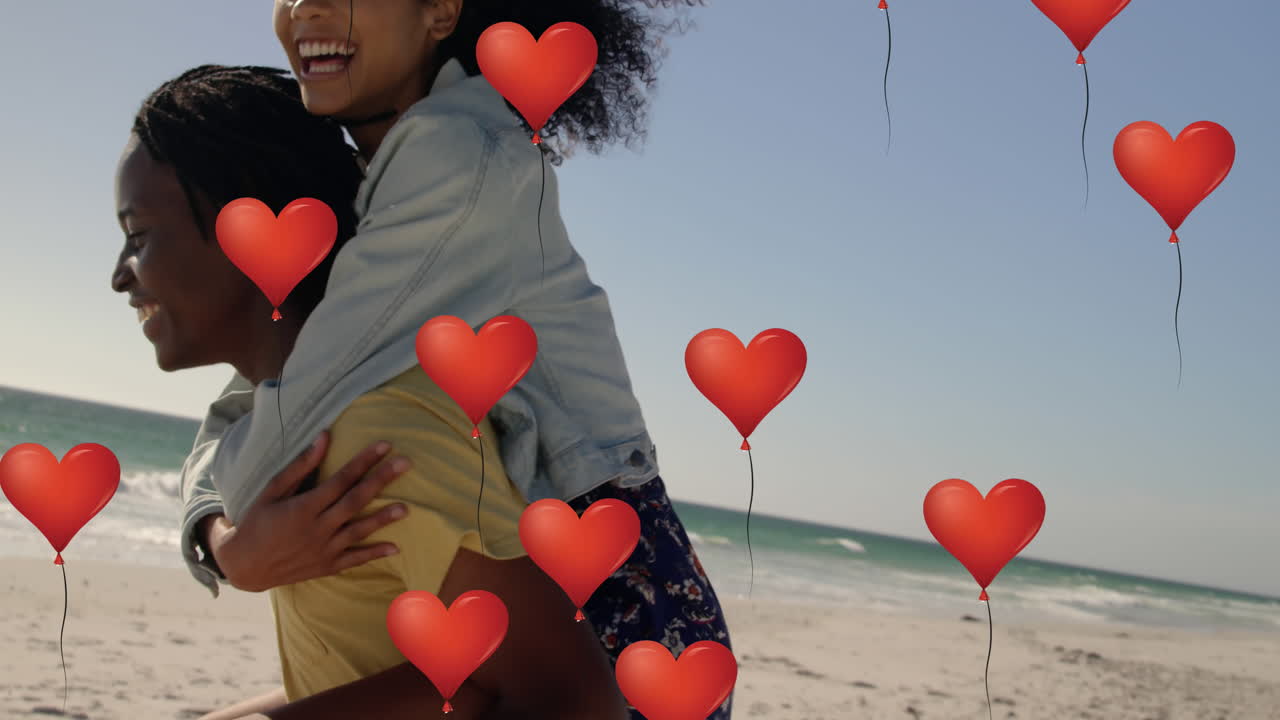 Multiple heart balloons floating against man giving piggyback ride to woman at beach