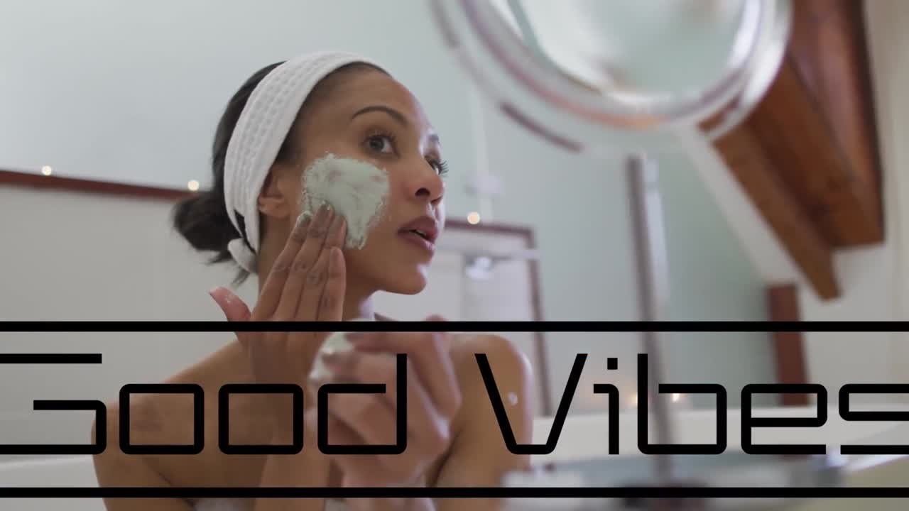 Animation of good vibes text over african american woman using cream in bathroom