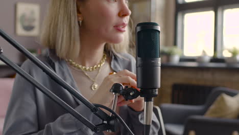 close up view of woman holding and talking into a microphone while recording a podcast