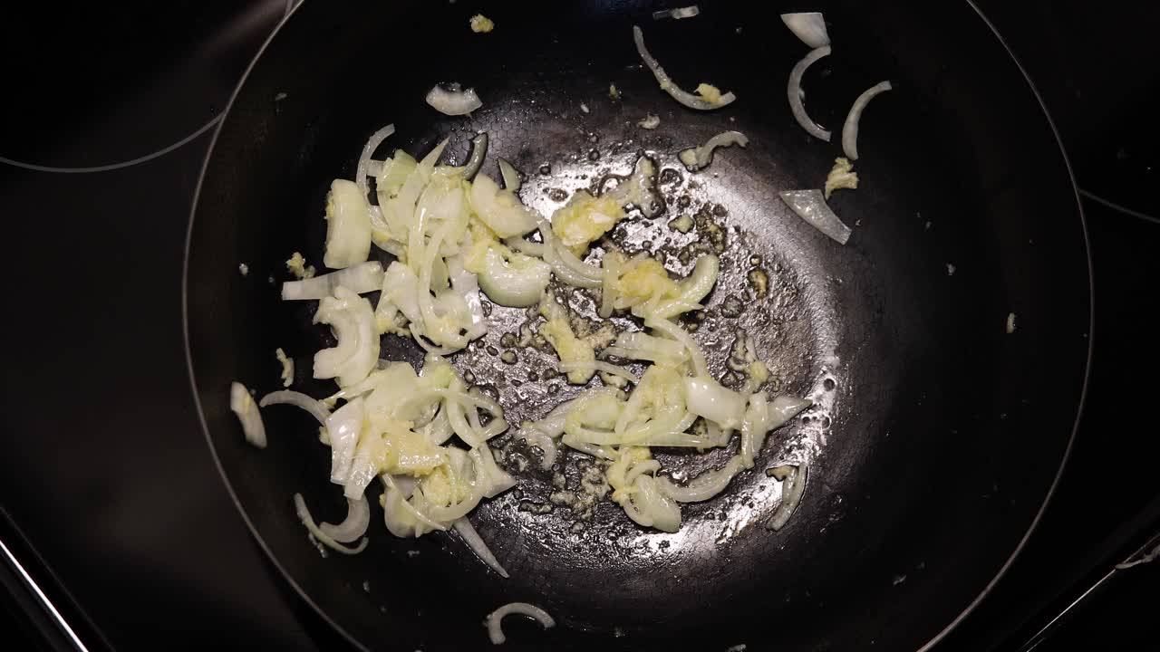 Frying onions in hot frying pan with butter sauce. Close up shot