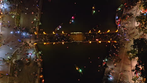 4k aerial view of hoi an at night with illuminated streets, glowing boats and colorful lanterns along the river